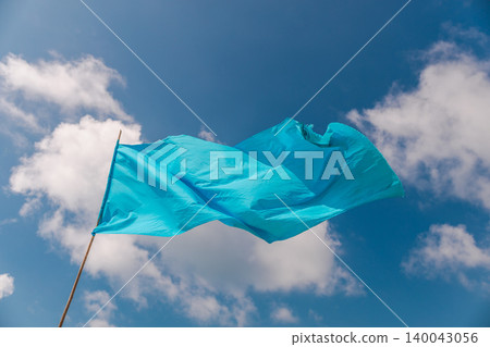 Blue warning flag fluttering in wind against sky with clouds on tropical beach Blue warning flag fluttering in wind against sky with clouds on tropical beach 140043056