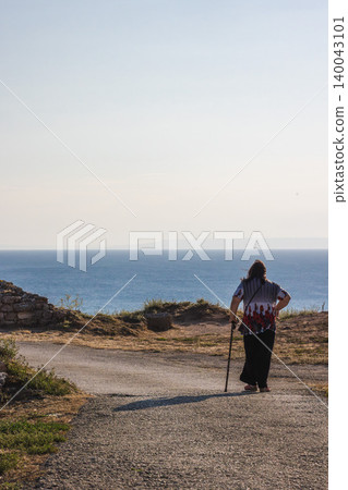 Senior woman with walking cane looking at Black Sea horizon on Cape Kaliakra Bulgaria 140043101