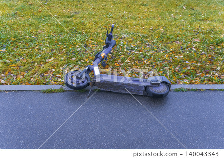 Wet pavement with abandoned scooter. Rainy sidewalk scene featuring discarded scooter and puddles nearby 140043343