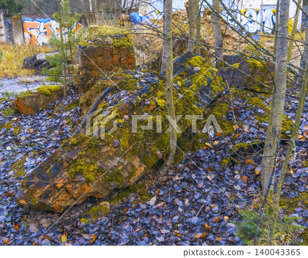 Nature reclaiming urban areas. Fallen leaves and mossy rocks. Serene scene of decay among young trees Nature reclaiming urban areas. Fallen leaves and mossy rocks. Serene scene of decay among young trees 140043365