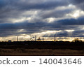 Dramatic sky with sun rays piercing through heavy clouds over an industrial landscape silhouette. Smokestacks puffing against the sunset 140043646