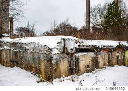 Deteriorated concrete and brick walls of a derelict building, blanketed in winter snow. A raw scene of urban abandonment, Russia 140043652