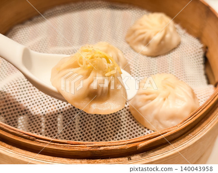 Steamed dishes. Xiao Long Bao, a Taiwanese dish made by steaming in a bamboo steamer. A picture of someone lifting a Xiao Long Bao topped with ginger with a spoon. 140043958