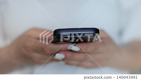 Hand of girl using smartphone in the living room at home, typing message. Close-up of young women hand. Hand of girl using smartphone in the living room at home, typing message. Close-up of young women hand. 140043991