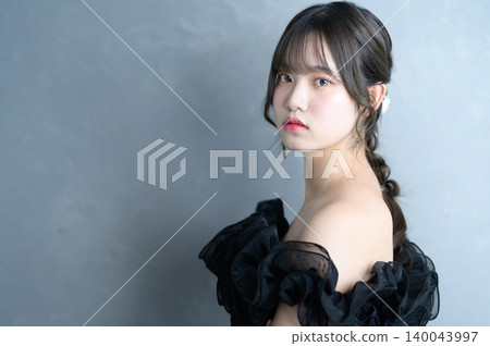 A Japanese woman in a black dress against a gray background. A Japanese woman in a black dress against a gray background. 140043997