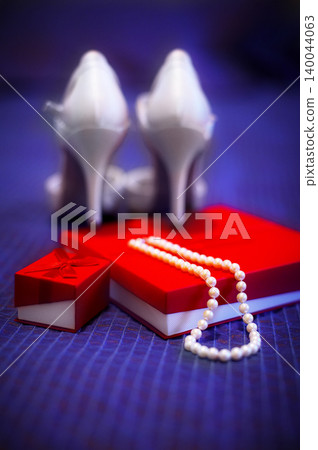 Bridal accessories flat lay with pearl necklace, red gift box and white high heel shoes Bridal accessories flat lay with pearl necklace, red gift box and white high heel shoes 140044063