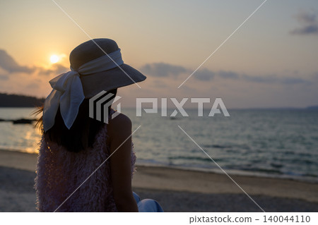 The back view of a Japanese woman watching the sunset in Okinawa. The back view of a Japanese woman watching the sunset in Okinawa. 140044110