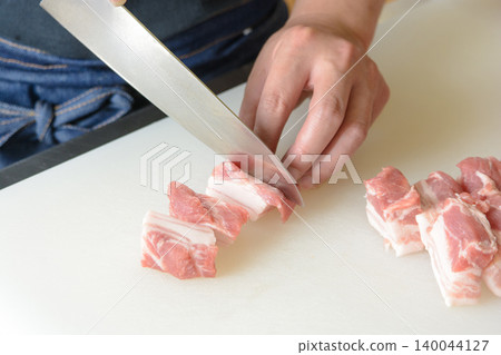 A scene of cutting pork belly with a knife during cooking. A scene of cutting pork belly with a knife during cooking. 140044127