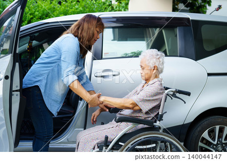 Caregiver help Asian elderly woman disability patient use wheelchair to get in car. Caregiver help Asian elderly woman disability patient use wheelchair to get in car. 140044147