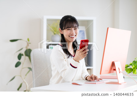 在辦公室使用智慧型手機的年輕女性 在辦公室使用智慧型手機的年輕女性 140044635