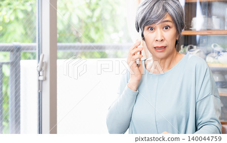 Senior woman making a phone call at home Senior woman making a phone call at home 140044759