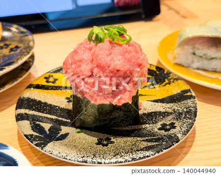 Negitoro gunkan sushi served on a conveyor belt sushi plate. Gunkan sushi topped with a mountain of negitoro. 140044940
