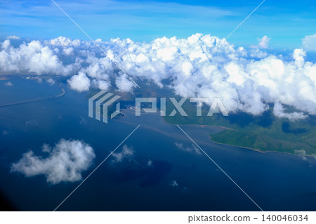 Looking through airplane window with the view of cloudscape. Fluffy white clouds with blue sky over the mountains in Hong Kong. Hong Kong rural area, Mountains from the high angle view. Nature scene. 140046034
