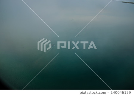 Looking through airplane window with the view of ocean of Hong Kong water. Ships sailing on the sea. Nature scene. 140046159