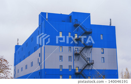 Zigzag staircase on striped facade. Silhouette of stairway against cloudy sky with safety rails 140046191