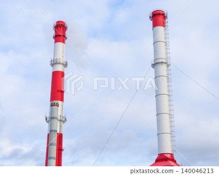Industrial chimney silhouette. Vertical twin chimneys with vibrant red collars dominate landscape Industrial chimney silhouette. Vertical twin chimneys with vibrant red collars dominate landscape 140046213