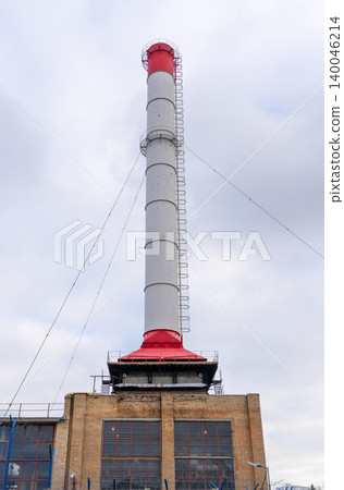 Chimney stands tall with cables. Vertical chimney with safety and emission monitoring attachments Chimney stands tall with cables. Vertical chimney with safety and emission monitoring attachments 140046214