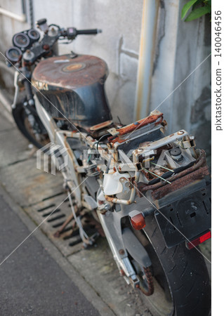 A photograph taken from a diagonal rear view, looking down on a sports bike that has been left neglected and decaying for many years. A photograph taken from a diagonal rear view, looking down on a sports bike that has been left neglected and decaying for many years. 140046456
