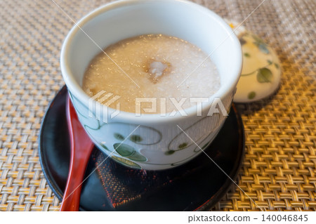 A pureed soup served in an elegant ceramic bowl, accompanied by a red spoon. 140046845