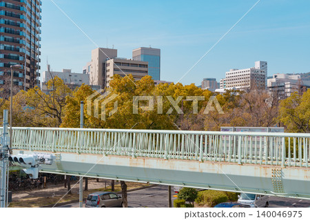 The city skyline stands out against the blue sky, and a mint-green pedestrian bridge docks. Modern urban infrastructure and a livable cityscape. The city skyline stands out against the blue sky, and a mint-green pedestrian bridge docks. Modern urban infrastructure and a livable cityscape. 140046975