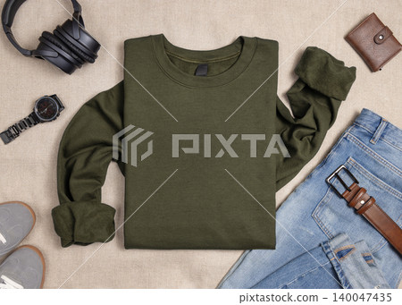 Blank green unisex sweatshirt mockup, folded crewneck with denim jeans and mens accessories Blank green unisex sweatshirt mockup, folded crewneck with denim jeans and mens accessories 140047435