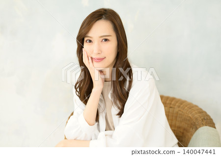 一位女士坐在椅子上，手托著下巴。 140047441