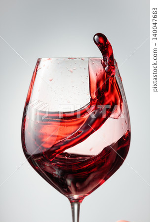 Wine glass with red liquid frozen in movement. Wine glass with red liquid frozen in movement. 140047683
