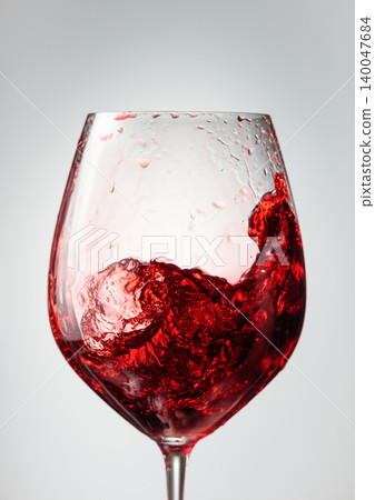 Wine glass with red liquid frozen in movement. Wine glass with red liquid frozen in movement. 140047684