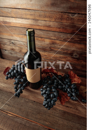 Red wine bottle with blue grapes on an old wooden table. Red wine bottle with blue grapes on an old wooden table. 140047696