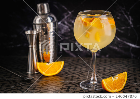 A glass of orange cocktail with ice cubes. 140047876