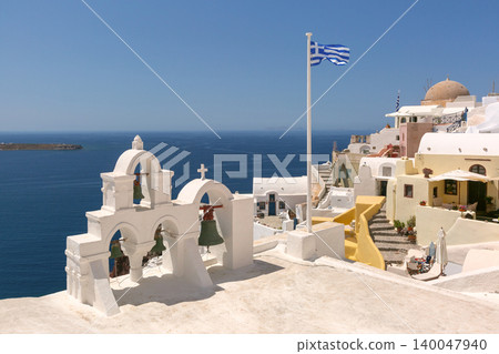 White bell tower and Greek flag above caldera in Santorini Greece White bell tower and Greek flag above caldera in Santorini Greece 140047940