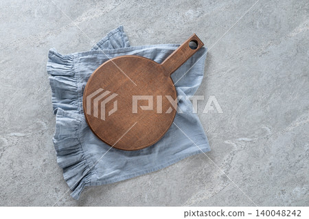 Wooden cutting board on blue linen napkin flat lay Wooden cutting board on blue linen napkin flat lay 140048242