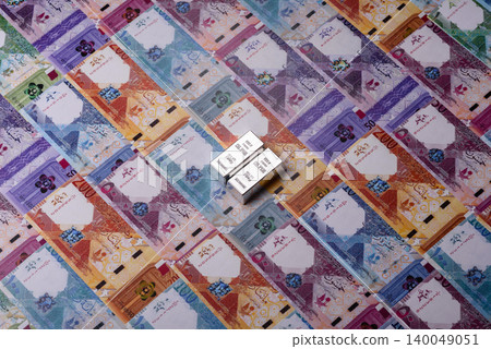 A silver bar, white metal against a backdrop of Qatari money, as a concept. A silver bar A silver bar, white metal against a backdrop of Qatari money, as a concept. A silver bar 140049051