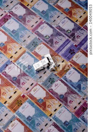 A silver bar, white metal against a backdrop of Qatari money, as a concept. A silver bar 140049053
