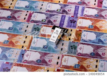 A silver bar, white metal against a backdrop of Qatari money, as a concept. A silver bar 140049054