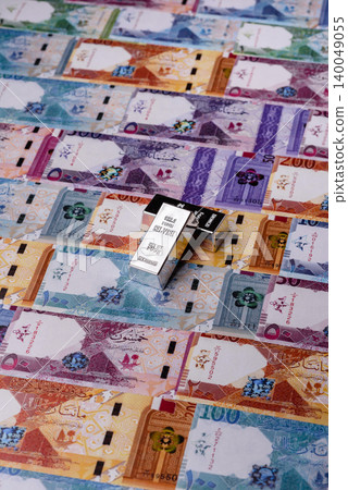 A silver bar, white metal against a backdrop of Qatari money, as a concept. A silver bar 140049055