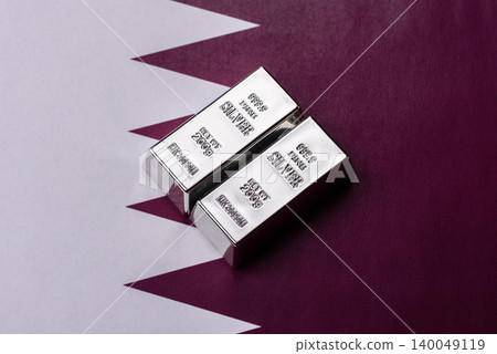 A silver bar, white metal against a backdrop of Qatari money, as a concept. A silver bar A silver bar, white metal against a backdrop of Qatari money, as a concept. A silver bar 140049119
