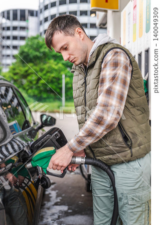 Young man refueling black car with gasoline nozzle at modern gas station in Germany Young man refueling black car with gasoline nozzle at modern gas station in Germany 140049309