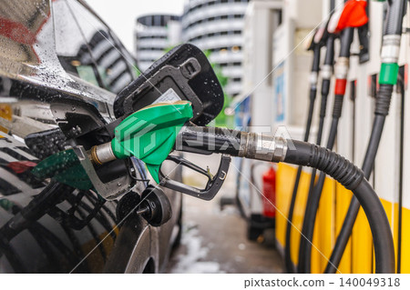 Refueling black car at gas station with green fuel nozzle on rainy day in Germany Refueling black car at gas station with green fuel nozzle on rainy day in Germany 140049318