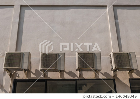 Four outdoor air conditioner units mounted on white commercial building wall Four outdoor air conditioner units mounted on white commercial building wall 140049349