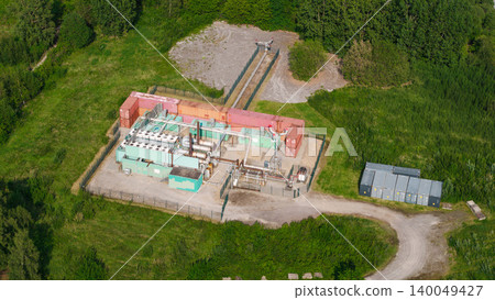 Aerial view of industrial energy facility with generators and pipelines surrounded by green landscape Aerial view of industrial energy facility with generators and pipelines surrounded by green landscape 140049427