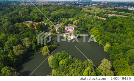 Aerial drone view of historic castle with lake surrounded by lush green forest near Essen Germany 140049429
