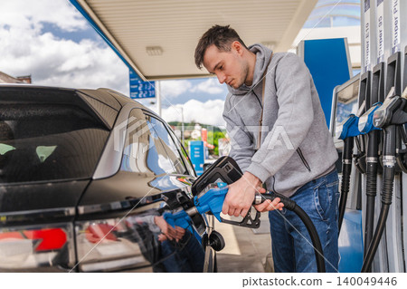 Young man refueling black car at modern gas station with gasoline pump during everyday transportation and travel 140049446