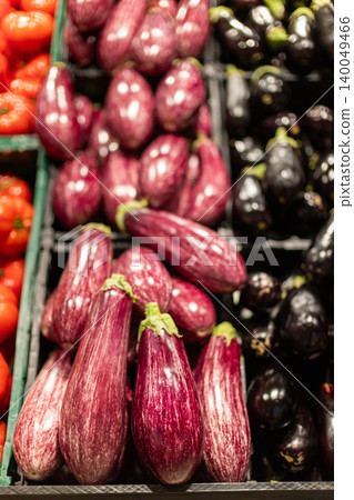 Fresh striped eggplants displayed in supermarket produce section, colorful organic aubergines arranged for healthy grocery shopping Fresh striped eggplants displayed in supermarket produce section, colorful organic aubergines arranged for healthy grocery shopping 140049466