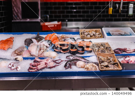 Fresh seafood and fish displayed on ice at supermarket counter, salmon fillets oysters and octopus at seafood market 140049496