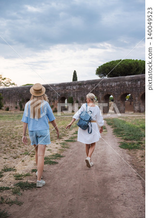 Mother and teenage daughter walking along path in Parco degli Acquedotti Rome toward ancient Roman aqueduct enjoying travel and family moment in Italy 140049523