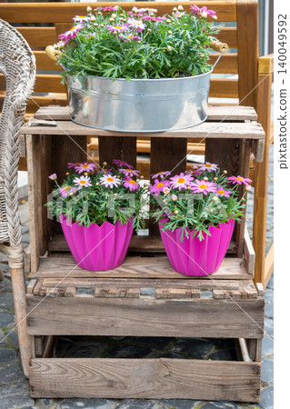 Wood romantic bench and pots with a lot of pink flowers. Outside decor, wood furniture in the garden near the house. Wood romantic bench and pots with a lot of pink flowers. Outside decor, wood furniture in the garden near the house. 140049592