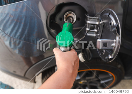 Hand refueling modern car with green fuel nozzle at gas station close up transportation and energy concept 140049793
