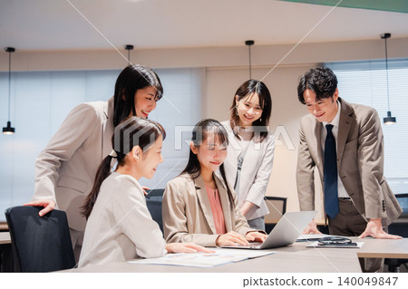 Employees smiling and looking at their computer screens as part of their office team. 140049847