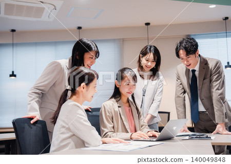 Employees smiling and looking at their computer screens as part of their office team. 140049848